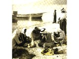 These Galilean fishermen, their boats anchored and their nets spread out to dry on the beach, have built a fire on an improvised hearth of stones. An early photograph.